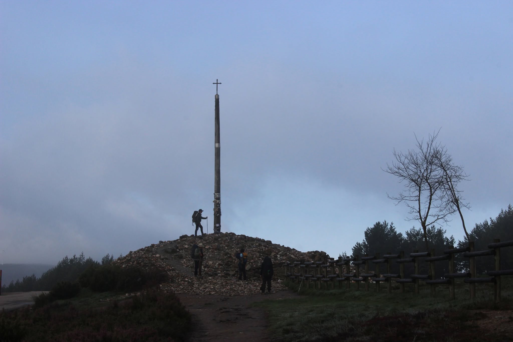 A pilgrim stands on a mound of intentions at the Cruz de Ferro.